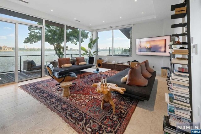 living room with a water view, a wall of windows, and light tile patterned flooring