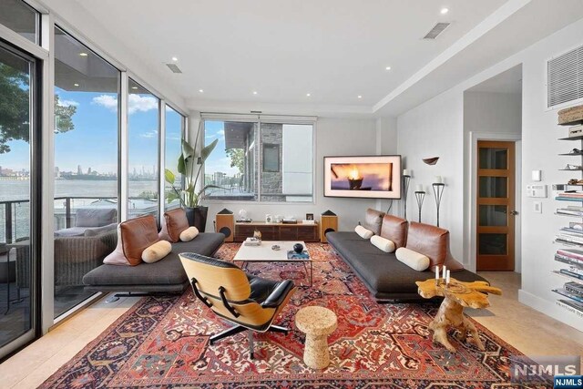 tiled living room with a water view and a wall of windows