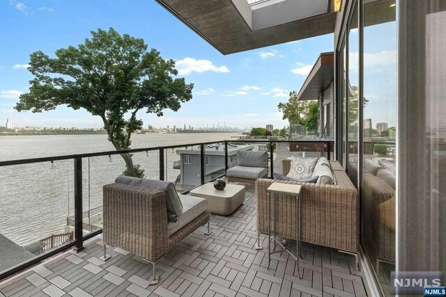 balcony featuring an outdoor living space and a water view