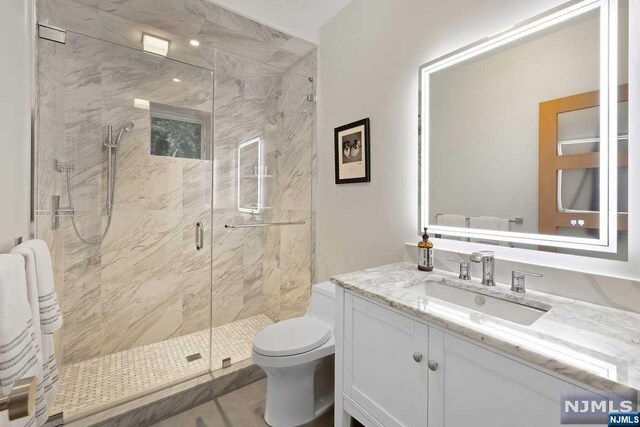 bathroom featuring vanity, toilet, and a shower with door