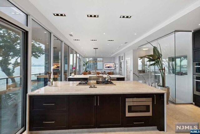 kitchen with light stone countertops, a center island, stainless steel appliances, decorative light fixtures, and a water view