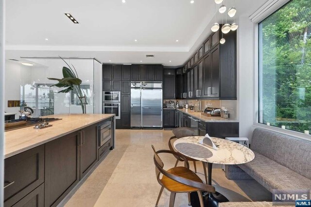 kitchen featuring built in appliances, decorative backsplash, and light tile patterned floors