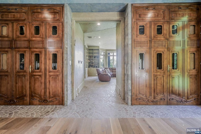 corridor with lofted ceiling and light wood-type flooring