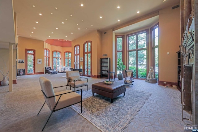 living room with light colored carpet, a healthy amount of sunlight, and a high ceiling