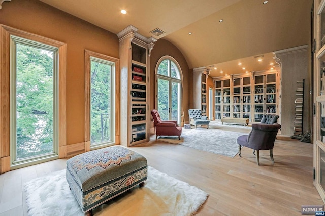 sitting room with light hardwood / wood-style floors, ornate columns, and a wealth of natural light