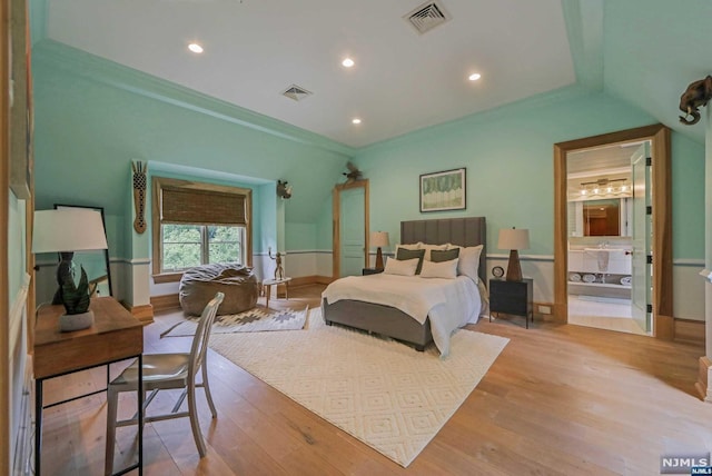 bedroom with connected bathroom, light hardwood / wood-style floors, and crown molding