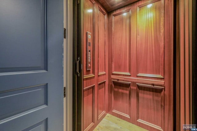 interior details featuring elevator, hardwood / wood-style flooring, and wooden walls