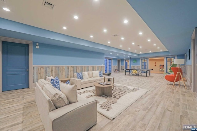 living room with light wood-type flooring and wooden walls