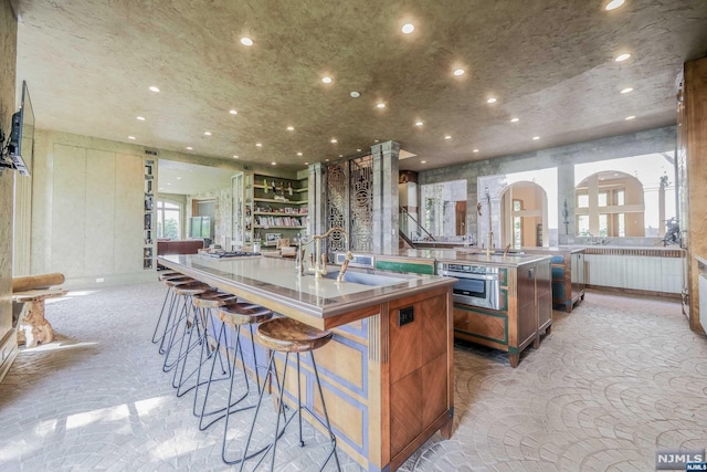 kitchen with sink, a kitchen breakfast bar, oven, a spacious island, and light carpet