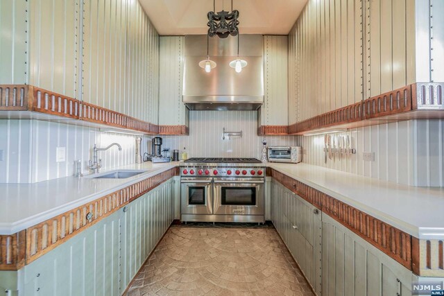 kitchen featuring pendant lighting, range with two ovens, and sink