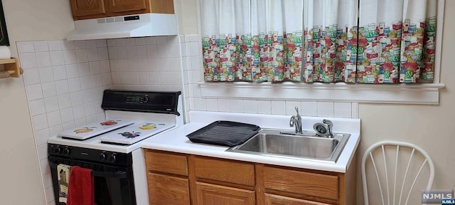 kitchen featuring decorative backsplash, white range, and sink