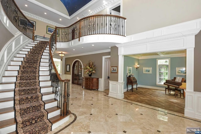 entryway with ornate columns, crown molding, and a towering ceiling