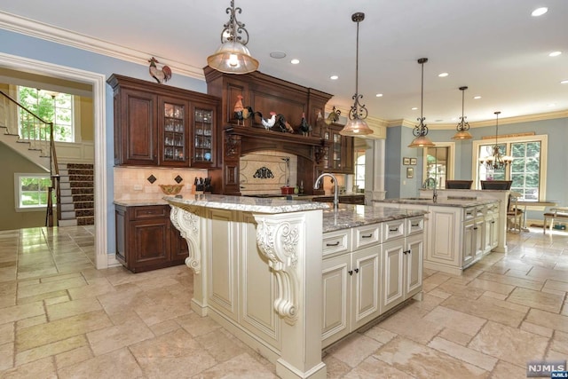 kitchen featuring backsplash, a wealth of natural light, a center island with sink, and pendant lighting