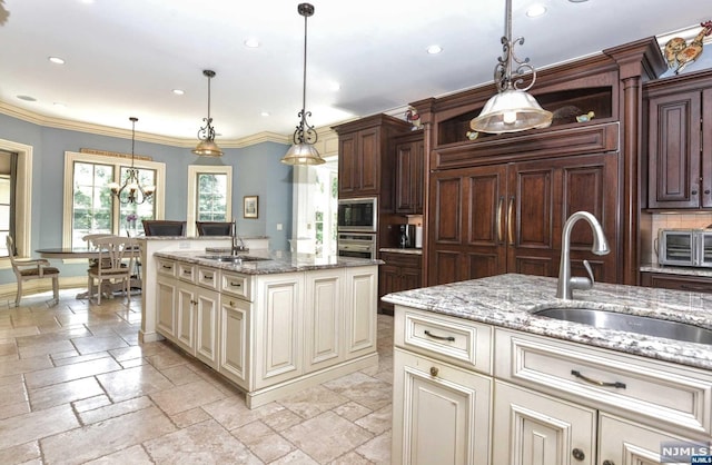 kitchen with decorative light fixtures, a center island with sink, and sink