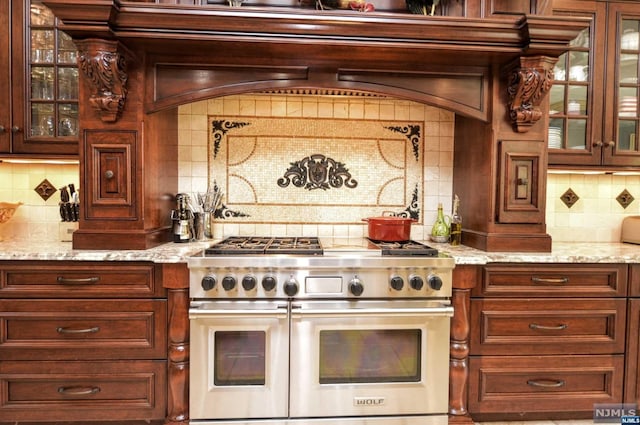 kitchen featuring light stone countertops, tasteful backsplash, and double oven range