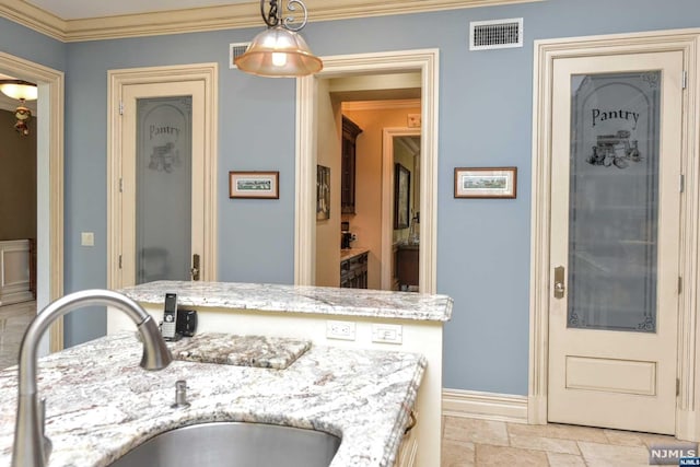 kitchen featuring light stone countertops, crown molding, sink, and pendant lighting