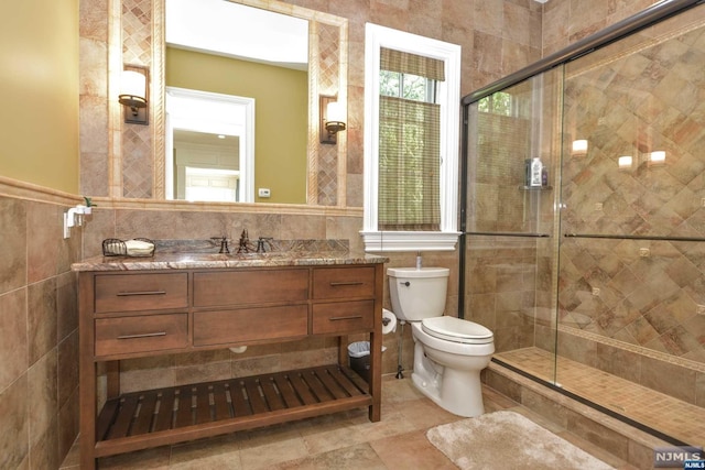 bathroom featuring vanity, toilet, an enclosed shower, and tile walls