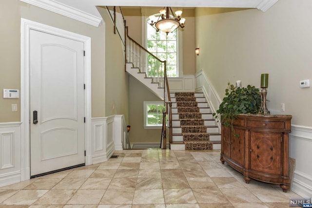 entrance foyer with plenty of natural light, crown molding, and a chandelier