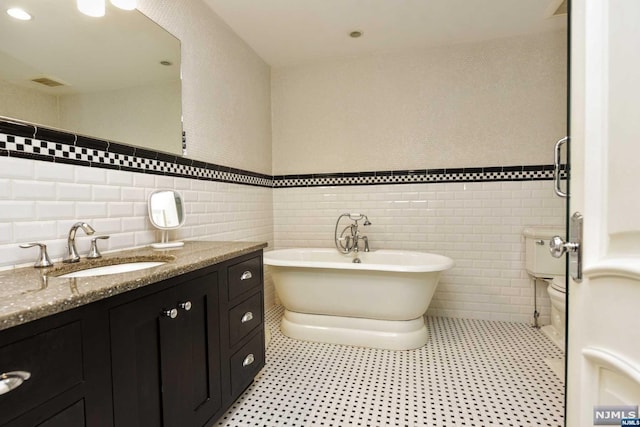 bathroom featuring a bathtub, vanity, and tile walls