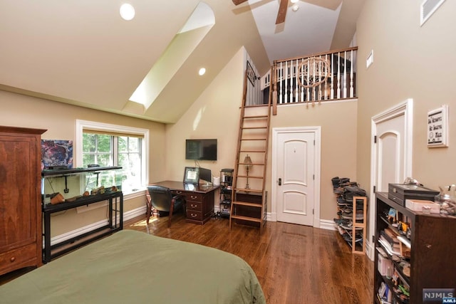 bedroom with a skylight, ceiling fan, dark hardwood / wood-style flooring, and high vaulted ceiling