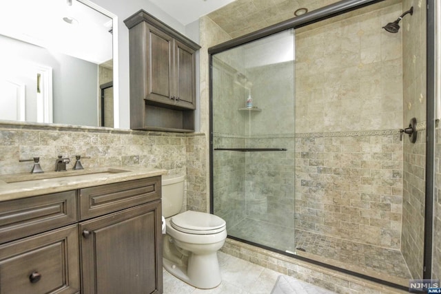 bathroom with vanity, toilet, walk in shower, and tile walls