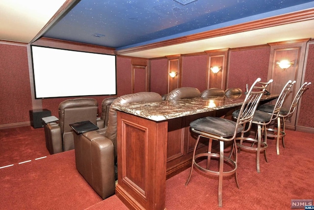 cinema room featuring dark carpet, ornamental molding, and bar area