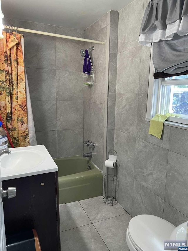 full bathroom with shower / bath combo, tile patterned flooring, toilet, vanity, and tile walls