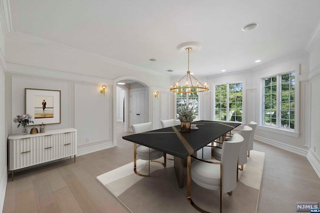 dining space featuring light wood-type flooring, an inviting chandelier, and crown molding