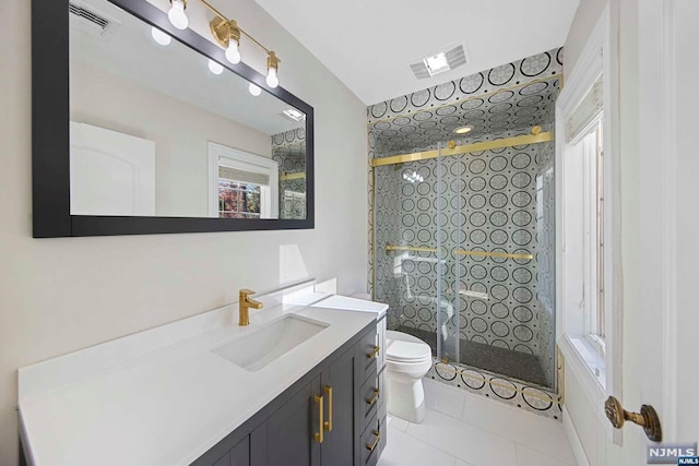 bathroom featuring tile patterned flooring, vanity, toilet, and walk in shower