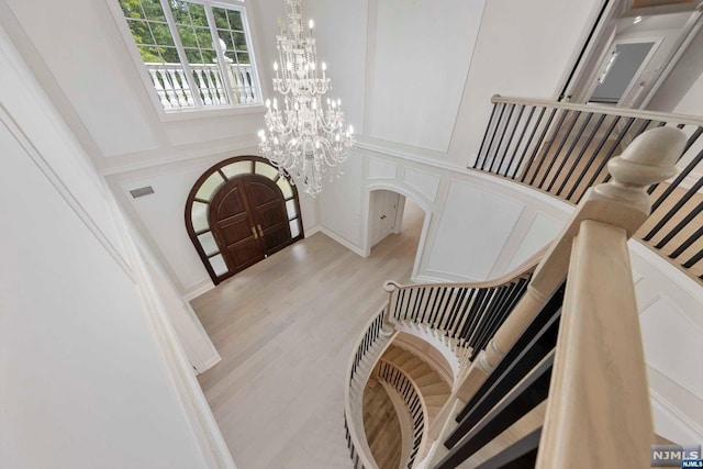 interior space featuring light hardwood / wood-style floors, a towering ceiling, and a chandelier