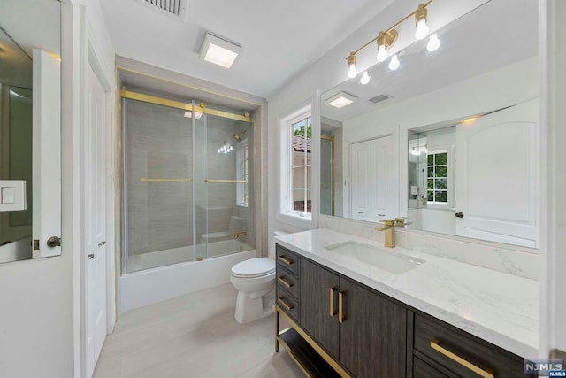 full bathroom with vanity, bath / shower combo with glass door, and toilet