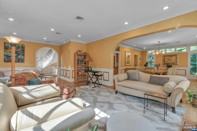 living room featuring light hardwood / wood-style flooring, ornamental molding, and a notable chandelier