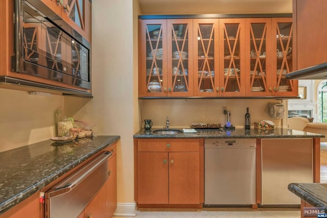 kitchen featuring dark stone counters, sink, and stainless steel appliances