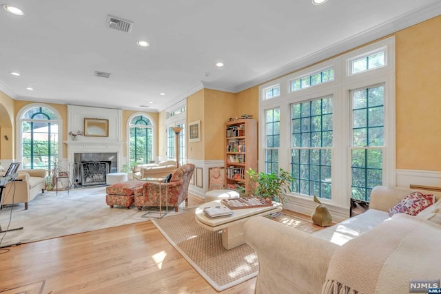 living room featuring plenty of natural light, a fireplace, and crown molding