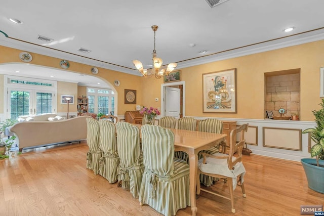 dining room with a chandelier, light hardwood / wood-style floors, crown molding, and french doors