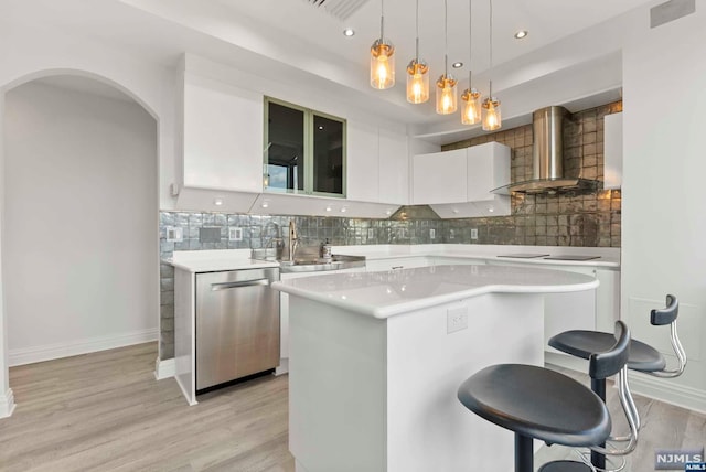 kitchen with white cabinetry, a center island, wall chimney exhaust hood, hanging light fixtures, and stainless steel dishwasher