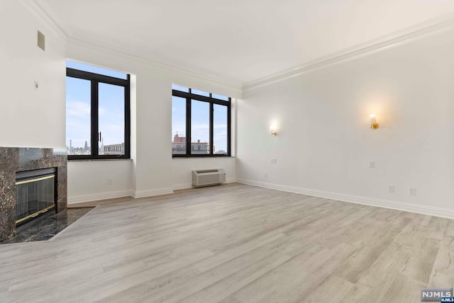 unfurnished living room featuring plenty of natural light, light hardwood / wood-style floors, a premium fireplace, and crown molding