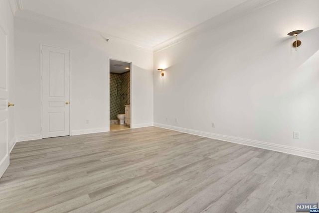 empty room with light hardwood / wood-style floors and crown molding