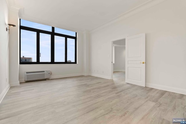 unfurnished room with light wood-type flooring, crown molding, and a wall mounted AC