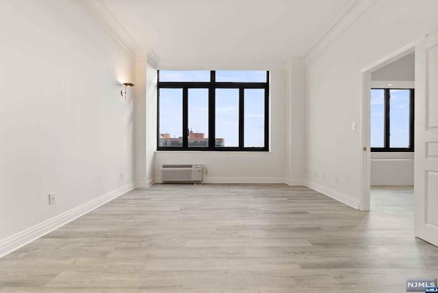 empty room featuring a wall mounted air conditioner, light wood-type flooring, and crown molding