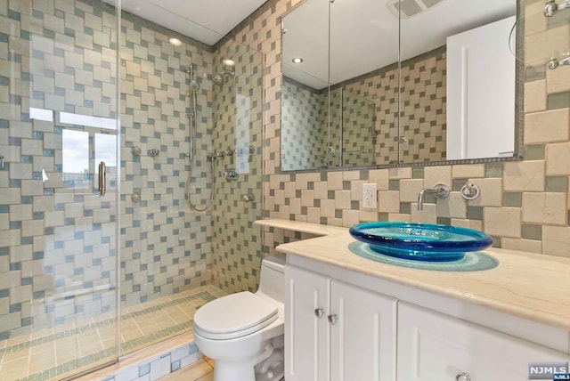 bathroom featuring walk in shower, tile walls, and toilet