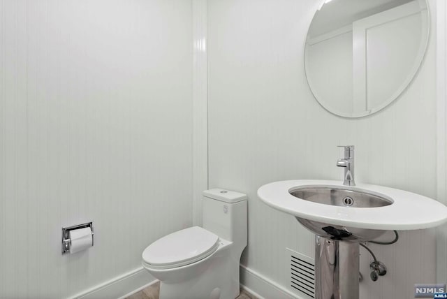 bathroom featuring wooden walls and toilet