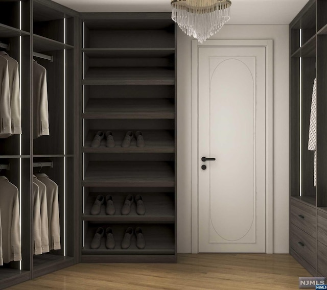 walk in closet with a chandelier and light hardwood / wood-style floors