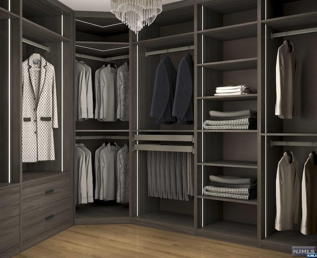 walk in closet with a notable chandelier and wood-type flooring