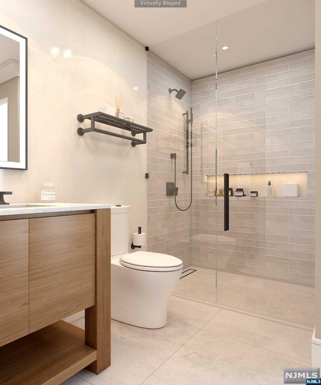 bathroom with tile patterned floors, vanity, toilet, and a tile shower