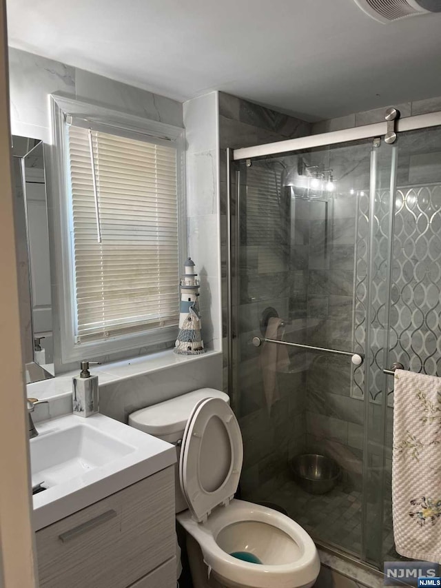 bathroom featuring walk in shower, vanity, and toilet