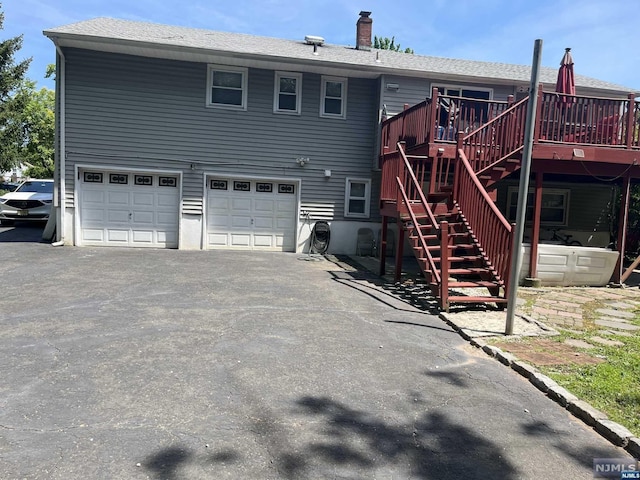 back of house featuring a garage and a wooden deck