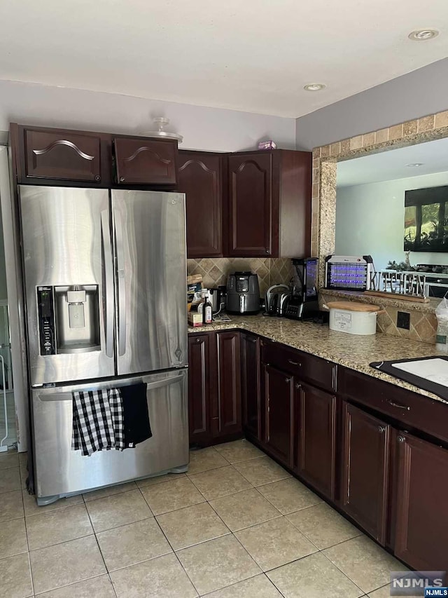 kitchen featuring light stone countertops, sink, stainless steel refrigerator with ice dispenser, backsplash, and light tile patterned flooring