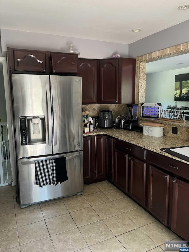 kitchen featuring decorative backsplash, stainless steel fridge with ice dispenser, light tile patterned floors, and dark brown cabinets