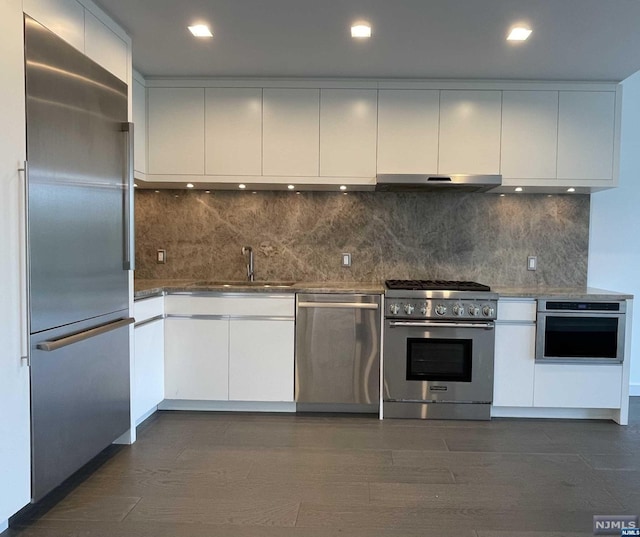 kitchen featuring backsplash, white cabinets, sink, dark hardwood / wood-style floors, and premium appliances